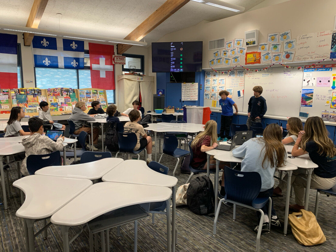 Two students debating at the front of the classroom during a flash debate, with a timer on the screen
